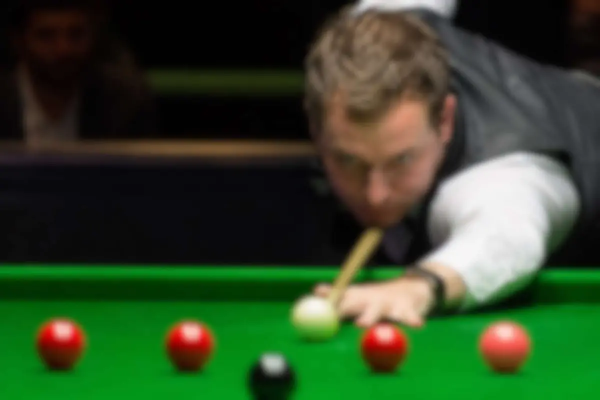 Snooker player lining up a shot over the cue ball at a club table